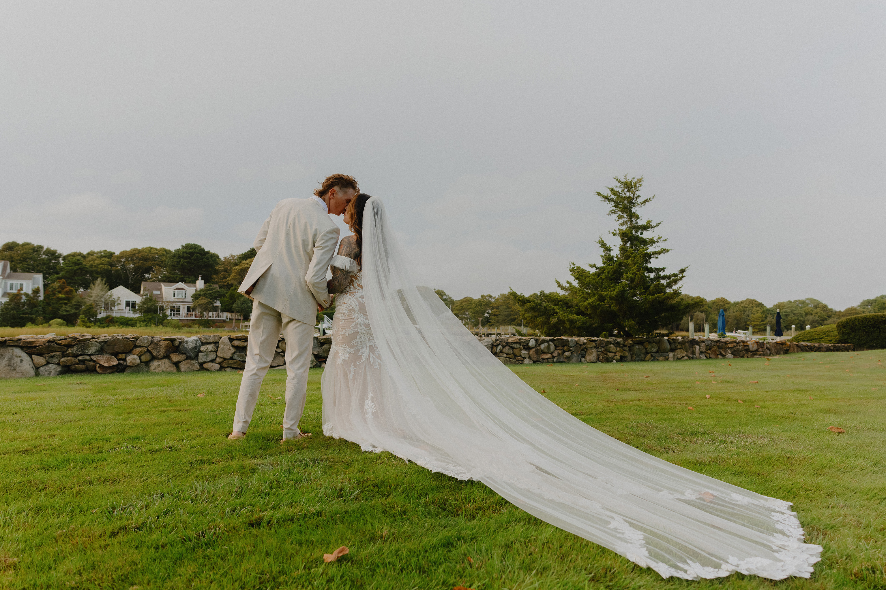 Cinematic long shot of a bride and groom walking through a green field